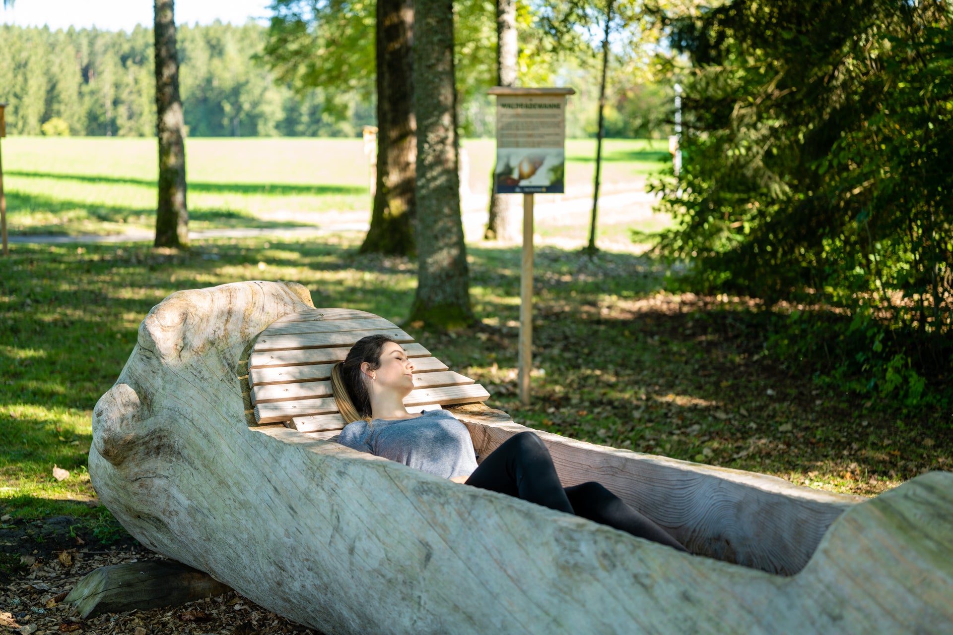 Frau entspannt in einer Waldbadewanne aus Holz im Kurpark